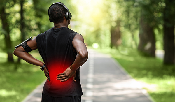 Jogger shown with back pain while stopping to rest during a run